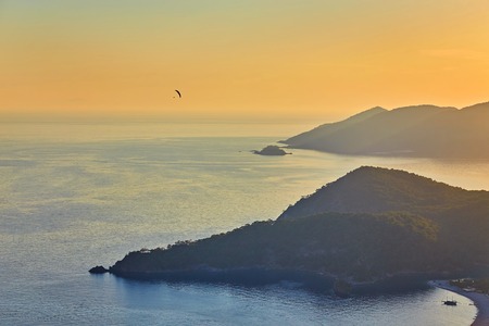 Amazing aerial view of beautiful sunset Blue Lagoon in Oludeniz, Turkey. Summer landscape with beach and mountains, green forest, azure water, sandy beach and blue sky in bright sunny day best touristの写真素材