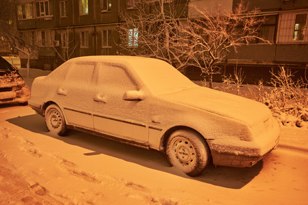 Snow-covered car after snowfall in night cityの写真素材