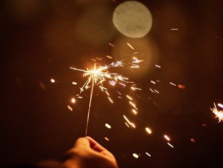 Woman holds glowing holiday sparkling hand fireworks, shining fire flame.の写真素材