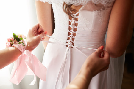 Helping the bride to put her wedding dress onの写真素材
