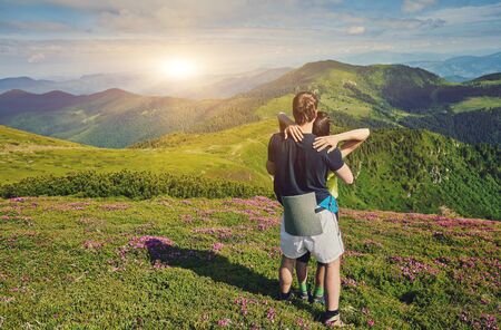 Couple of tourists are standing at the top of a mountain with a feeling of freedom.の写真素材