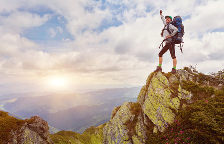 successful young woman backpacker open arms on mountain peak