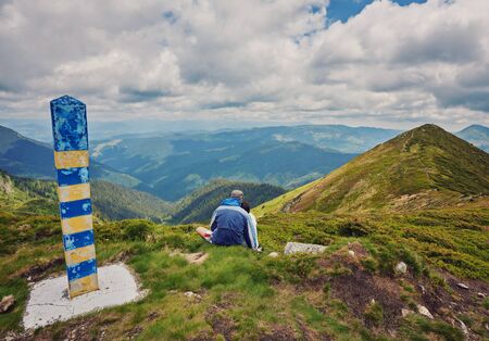 Young couple sitting on rock and enjoying beautiful viewの写真素材