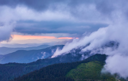 Mountain peaks with clouds approaching them, landscape at sunset