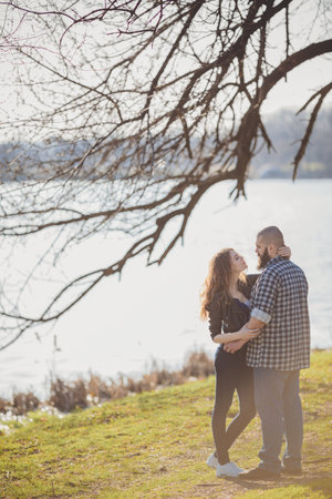 young and stylish couple standing near water in a spring park