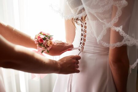 Helping the bride to put her wedding dress onの写真素材