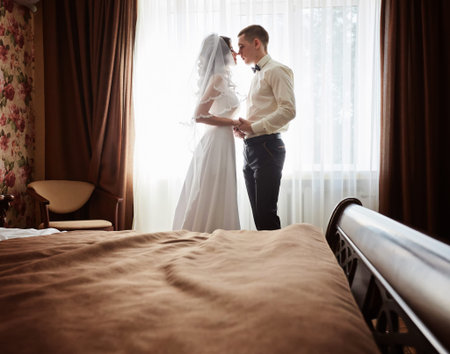 The first meeting of the bride and groom on the wedding day. Emotions newlyweds before the wedding ceremony. Bride and groom look at each other, hugging and kissing.の写真素材