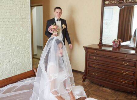 The first meeting of the bride and groom on the wedding day. Emotions newlyweds before the wedding ceremony. Bride and groom look at each other, hugging and kissing.の写真素材