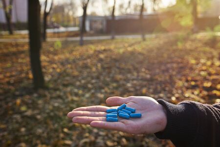 Close up of male hands with blue pills in hand. Natural background. Cure concept.の写真素材