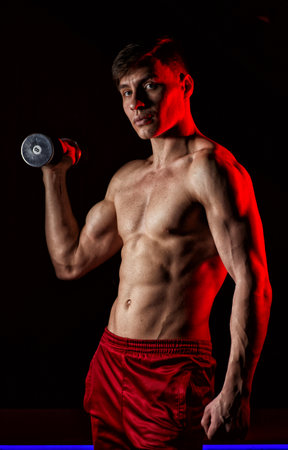 Muscular athlete man exercise on a black background. Red background lightの写真素材