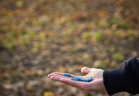 Close up of male hands with blue pills in hand. Natural background. Cure concept.