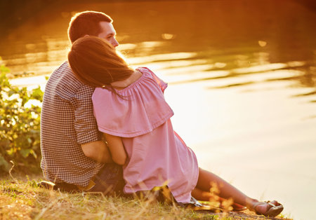 Enjoying By The River.Romantic smiling couple in love dating at sunset at river.の写真素材