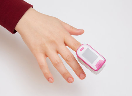 Pulse Oximeter, finger digital device to measure oxygen saturation in blood. Reduced oxygenation is an emergency sign of pneumonia, for instance caused by coronavirus. Device on Caucasian female hand.の写真素材