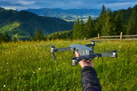Start the drone, launching from hands. Modern small copter with camera in user hand, against sky....