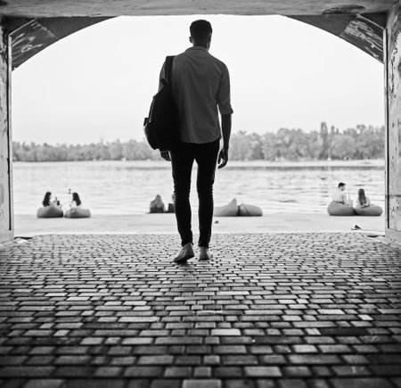 Young european man standing on a city street with a backpackの写真素材