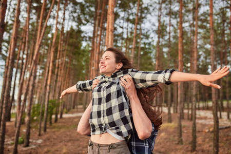 young couple smiling at each other during a romantic date in the forest - strong sunlight - shot against sunの写真素材
