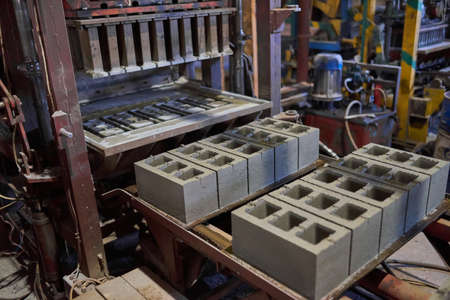 Industrial production of building materials from pressed cement mortar. High quality hollow concrete block or cement brick. Finished products stacked on pallets dry after the press.の写真素材