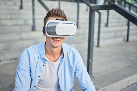 Young man with glasses of virtual reality on the street. Live emotions from viewing virtual reality