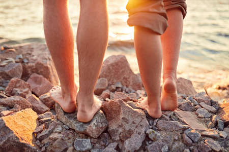 Legs on beach. Foot spa. A young loving couple hugging and kissing on the beach at sunset. Two lovers, man and woman barefoot near the water. Summer in loveの写真素材