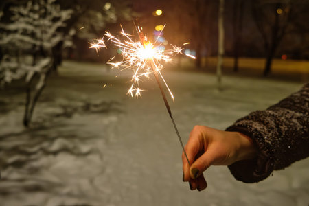 The girl walks in the Christmas park with festive lights in the evening. Feel happy in a big city.