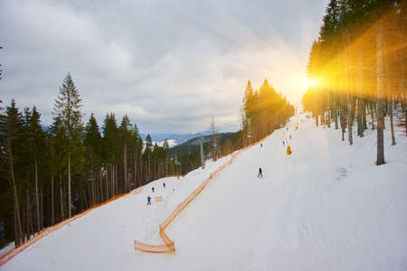 Ski resort in beautiful sunset light. View from the top: ski tracks, pine tree forest and mountains in the background. Winter holidays in Bukovel, Carpathians, Ukraine, Europeの写真素材
