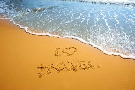 handwritten words I love travel on sand of tropical beach with wave on backgroundの写真素材