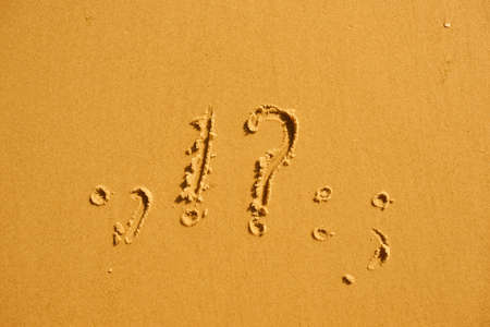 Question marks and exclamations in summer on the beach sandの写真素材