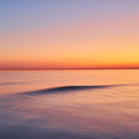 Vivid twilight sunset sky and motion blur of the sea under with long exposure effect.の写真素材