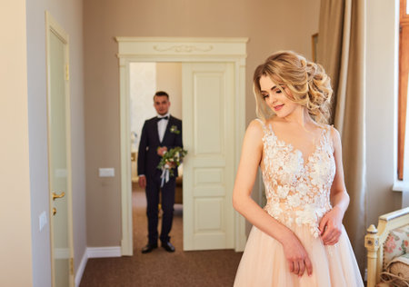 Happy handsome groom with bouquet entering roomの写真素材