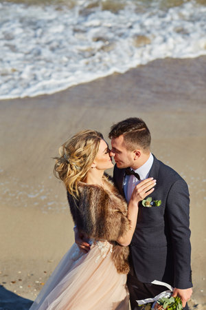 Happy young newly married couple woman in white dress man in love running, have fun on clean sandy beach waves of azure sea or ocean, summer vacation at water. Wedding rest, relax honeymoon concept.の写真素材