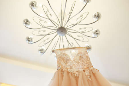 Luxury wedding dress hanging on the chandelier in a hotel room. bridal gown. Bridesmaids. Weddingの写真素材