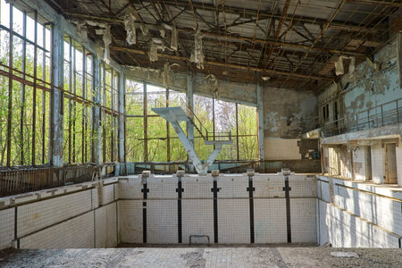 Abandoned swimming pool in Pripyat. Destroyed gym in a radioactive city. The street is overgrown with trees and bushes. jumping tamplin.のeditorial素材
