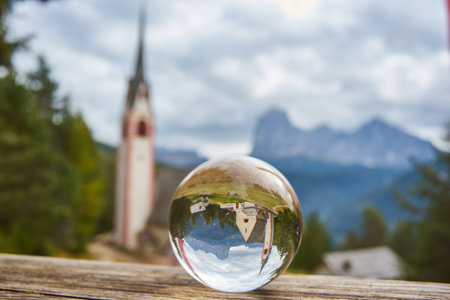 Photo through a glass ball. Church of San Giacomo. Ortisei, Gardena Valley, South Tyrol, Dolomites, Italy, Europe.の写真素材