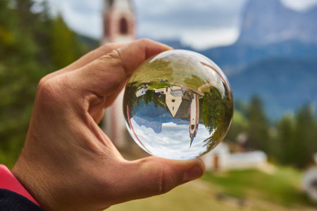 Photo through a glass ball. Church of San Giacomo. Ortisei, Gardena Valley, South Tyrol, Dolomites,...