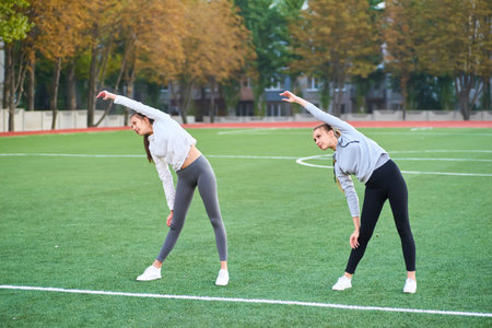 Two women doing fitness workout in active wear in nature. Concept of healthy lifestyle.