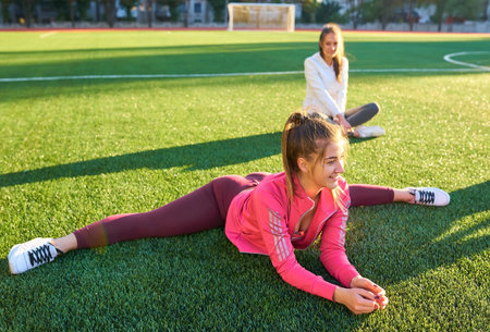 Two beautiful sports girls exercising together on a lawn in the early morning.の写真素材