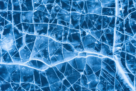 Ice on a frozen river. Background texture of blue ice with cracks in the snow. drone top view.の写真素材