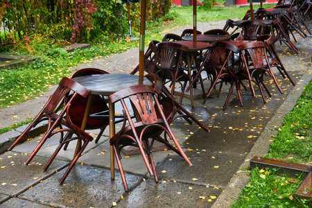 Wooden chairs leaning on tables in closed cafe or restaurant during the morning after the rainの写真素材