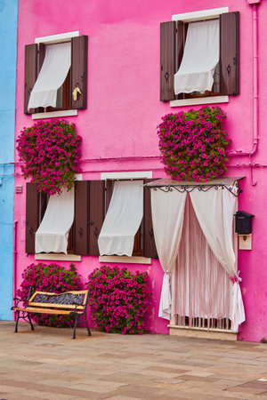 Door and window with flower on the red facade of the house. Colorful architecture in Burano island, Venice, Italy.の写真素材