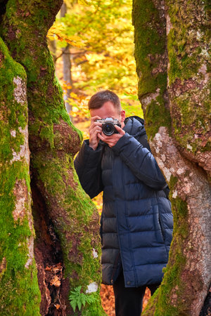 Young Caucasian Male Photographer Taking Picture in the autumn parkの写真素材