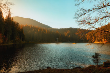 Immerse yourself in the breathtaking beauty of the Carpathian Mountains during autumn. The captivating Synevir Lake reflects the vibrant colors of the surrounding foliage. Lose yourself in the tranquility of this serene landscape, where nature's palette comes alive with hues of gold, orange, and redの写真素材