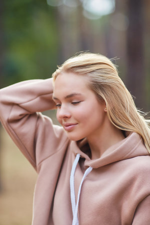 Young blonde woman smiling happy walking at the park. Portrait of a joyful young woman enjoying in autumn park.の写真素材