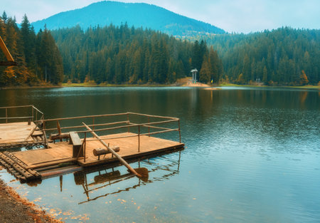 Immerse yourself in the breathtaking beauty of the Carpathian Mountains during autumn. The captivating Synevir Lake reflects the vibrant colors of the surrounding foliage. Lose yourself in the tranquility of this serene landscape, where nature's palette comes alive with hues of gold, orange, and redの写真素材