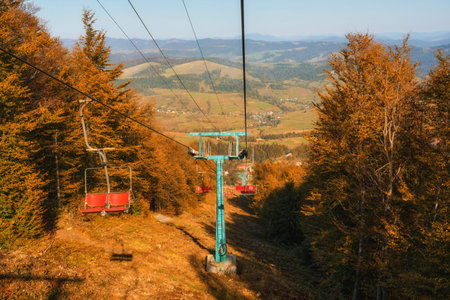 This captivating photo features an old cable car nestled in the backdrop of picturesque autumn mountains, basking in the warm glow of a sunny day. It exudes a sense of nostalgia and rugged beauty, blending nature and human engineering.の写真素材