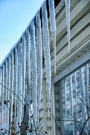 Huge icicles hang from the facades of buildings. The fall of icicles carries a danger to people's lives.の写真素材