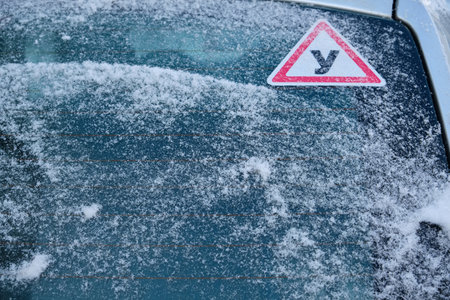 A car parked in the snow, its window covered with a thick layer of snow, creating a winter wonderland scene and highlighting the chilly weather.の写真素材
