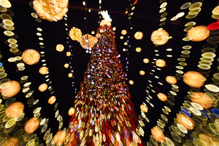 Blurred christmas tree with lights decorations outdoors at night. New Year Celebration.の写真素材
