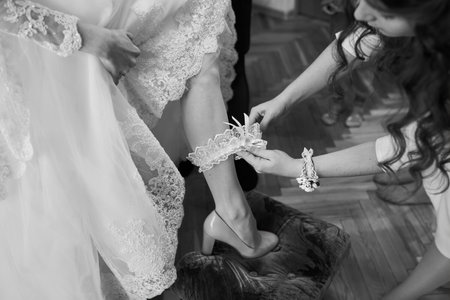 bridesmaid buttoning the dress on bride, details of beautiful lace wedding dressの写真素材