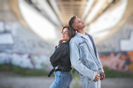 A fashionable and youthful couple exudes style and love while striking poses on the city streets.