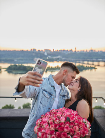 A young man surprises his beloved with a vast bouquet of roses as they capture their joy in a selfie...
